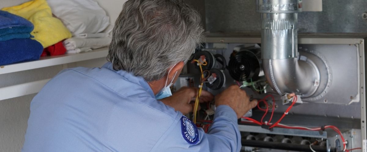 Image of an HVAC technician performing service on a Carrier furnace.