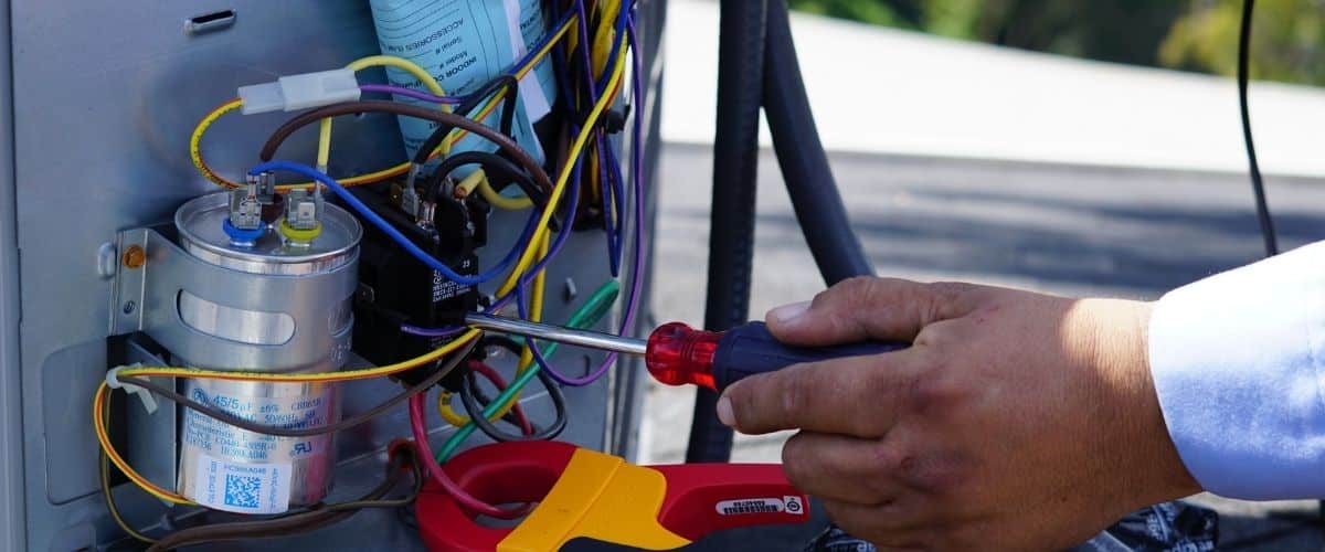 Image of an HVAC technician performing repairs on a residential air conditioner